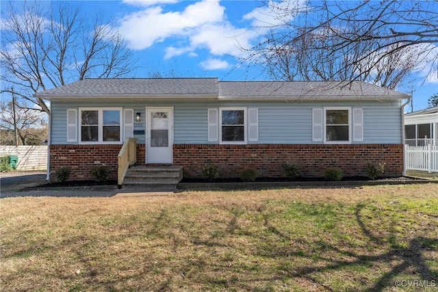 view of front of house featuring entry steps, a front lawn, fence, and brick siding