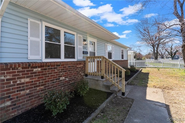 doorway to property with brick siding and fence