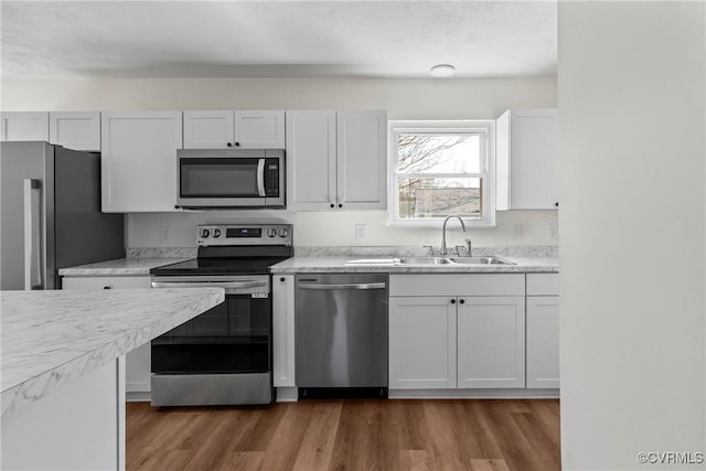 kitchen with dark wood-style flooring, a sink, stainless steel appliances, light countertops, and white cabinets