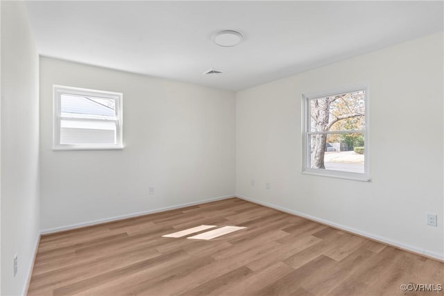 spare room featuring visible vents, baseboards, and light wood-style floors