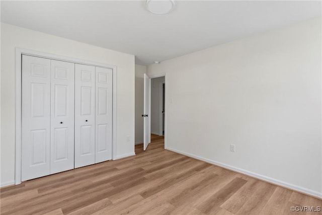 unfurnished bedroom featuring light wood-style flooring, baseboards, and a closet