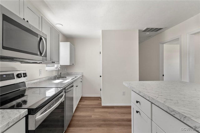 kitchen featuring visible vents, light countertops, light wood-style floors, stainless steel appliances, and a sink