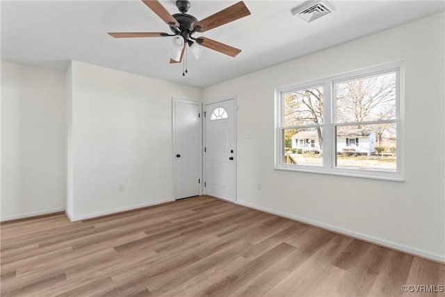 spare room featuring light wood-type flooring, visible vents, baseboards, and ceiling fan