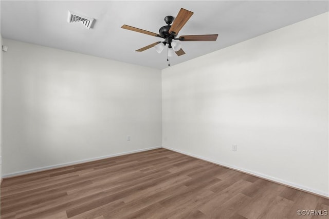 unfurnished room with ceiling fan, visible vents, baseboards, and wood finished floors