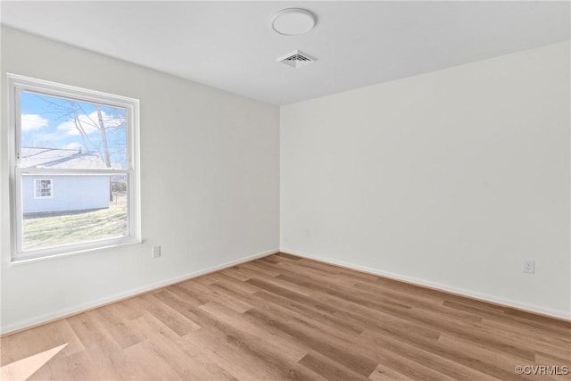 unfurnished room with visible vents, light wood-style flooring, and baseboards