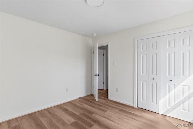 unfurnished bedroom featuring light wood finished floors, a closet, and baseboards