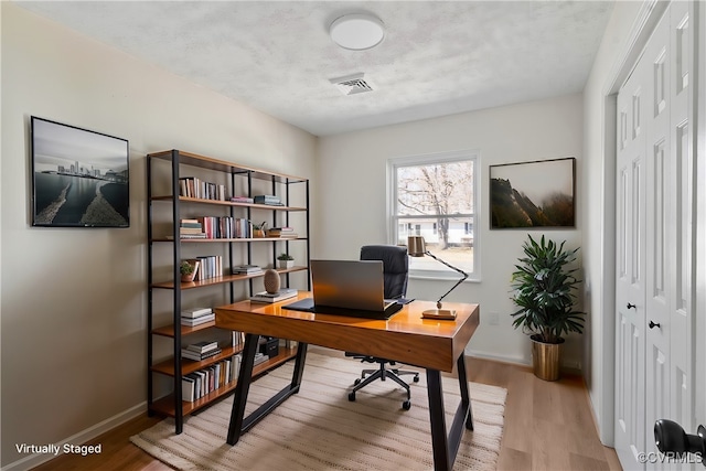 office area with visible vents, baseboards, and wood finished floors