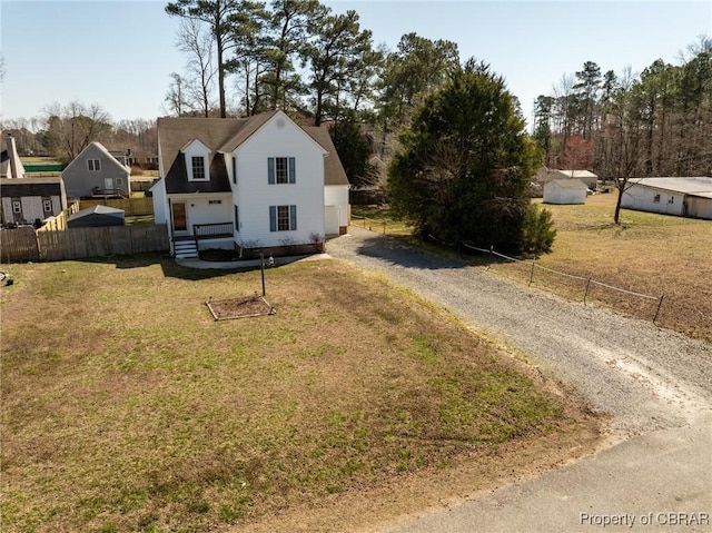 view of front facade featuring a chimney, gravel driveway, a front lawn, and fence