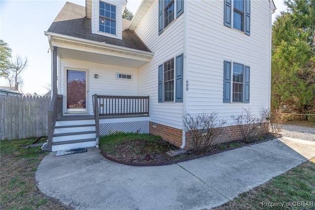 property entrance featuring fence, roof with shingles, and crawl space