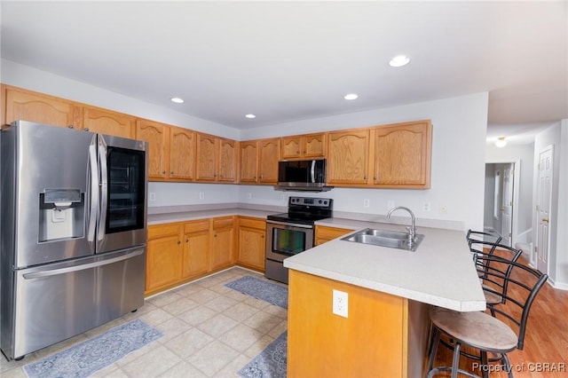 kitchen featuring a peninsula, stainless steel appliances, light countertops, and a sink