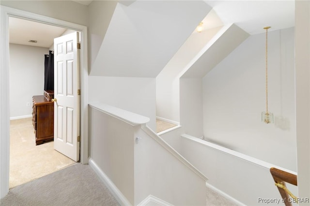 hall with an upstairs landing, carpet flooring, and baseboards