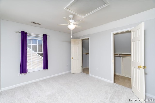 unfurnished bedroom featuring visible vents, a walk in closet, carpet, baseboards, and ceiling fan