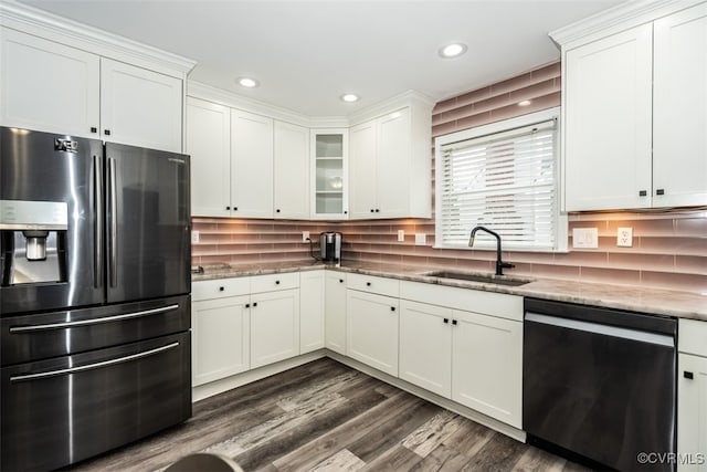 kitchen with light stone countertops, a sink, dark wood-type flooring, appliances with stainless steel finishes, and backsplash