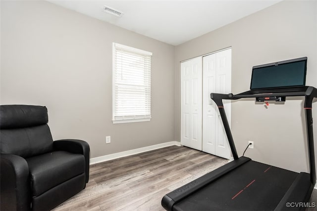 workout area featuring wood finished floors, visible vents, and baseboards