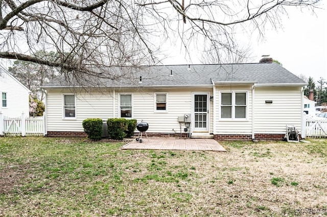 back of property with a patio, fence, a yard, roof with shingles, and a chimney