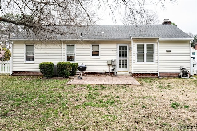 rear view of house with fence, roof with shingles, a chimney, a yard, and a patio area