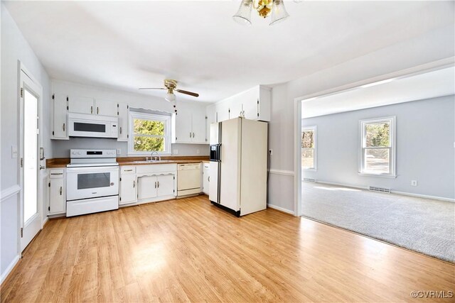 kitchen featuring visible vents, a sink, white appliances, white cabinets, and ceiling fan