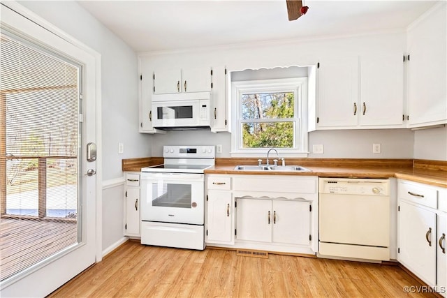 kitchen featuring white appliances, white cabinets, light wood finished floors, and a sink