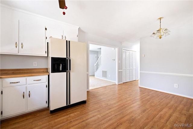 kitchen featuring visible vents, light wood-type flooring, an inviting chandelier, white fridge with ice dispenser, and white cabinetry