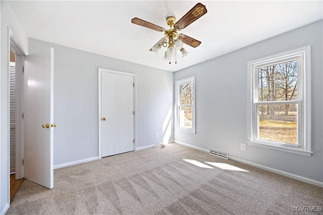 unfurnished bedroom featuring visible vents, baseboards, carpet, and a ceiling fan