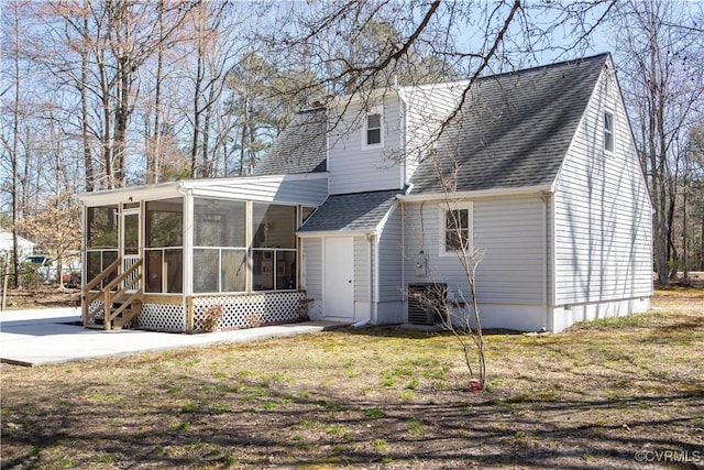 rear view of house featuring a patio, a yard, a sunroom, and roof with shingles