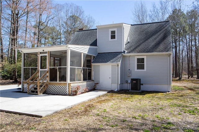 back of house featuring central AC unit, roof with shingles, and a sunroom