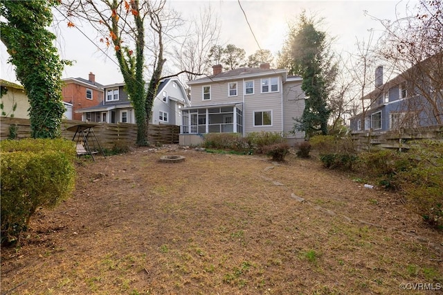 back of house featuring fence, a sunroom, and a chimney