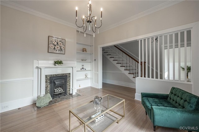 living area featuring a notable chandelier, built in features, crown molding, and wood finished floors