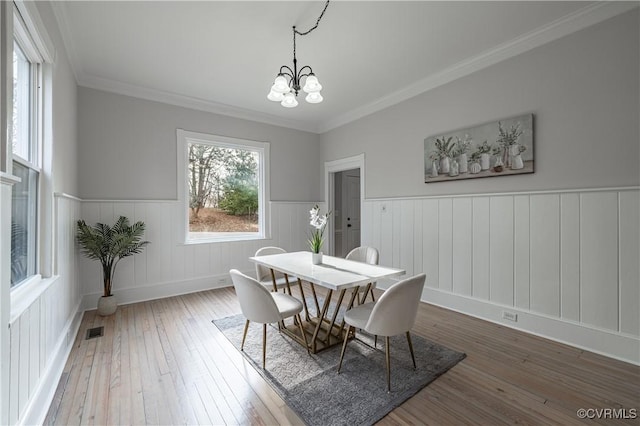 dining area with visible vents, ornamental molding, hardwood / wood-style flooring, wainscoting, and a chandelier