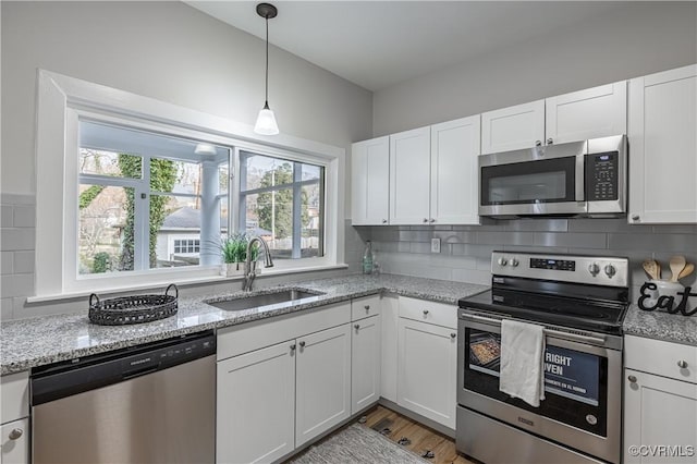 kitchen featuring decorative backsplash, white cabinetry, appliances with stainless steel finishes, and a sink