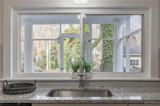 room details featuring light stone counters and a sink