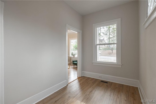 spare room with visible vents, baseboards, and wood finished floors