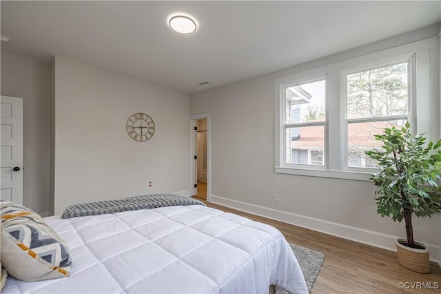 bedroom featuring visible vents, baseboards, and wood finished floors