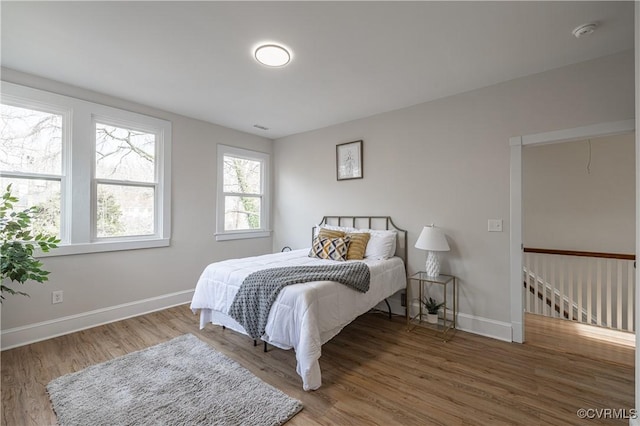 bedroom with visible vents, baseboards, and wood finished floors