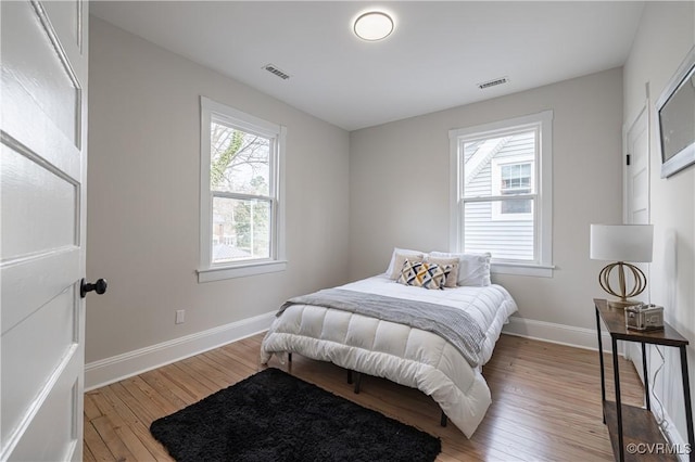 bedroom with visible vents, light wood-type flooring, and baseboards