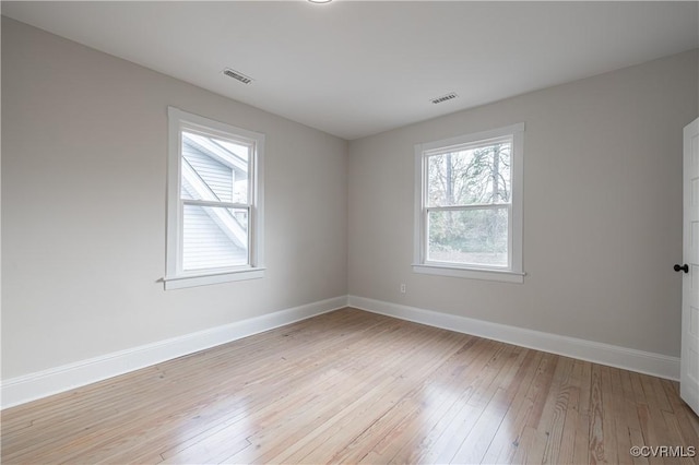 empty room featuring visible vents, baseboards, and light wood finished floors