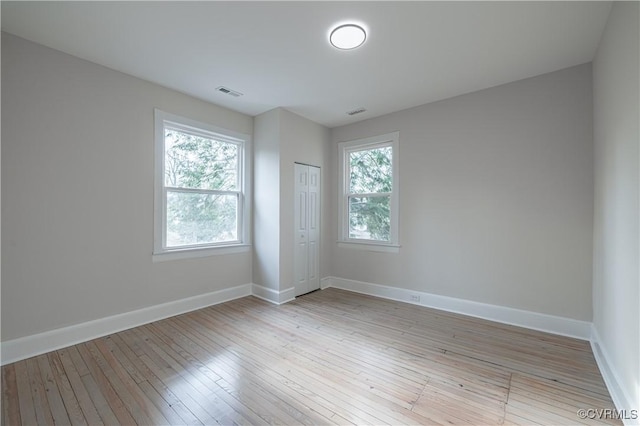 spare room with a wealth of natural light, visible vents, and baseboards