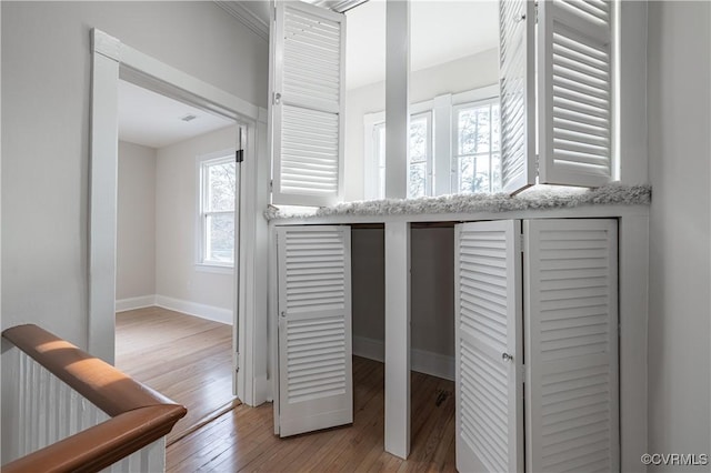 corridor featuring light wood-type flooring and baseboards