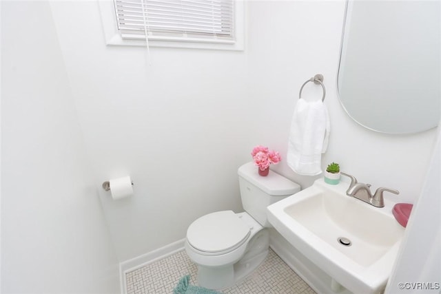 bathroom with tile patterned flooring, toilet, baseboards, and a sink