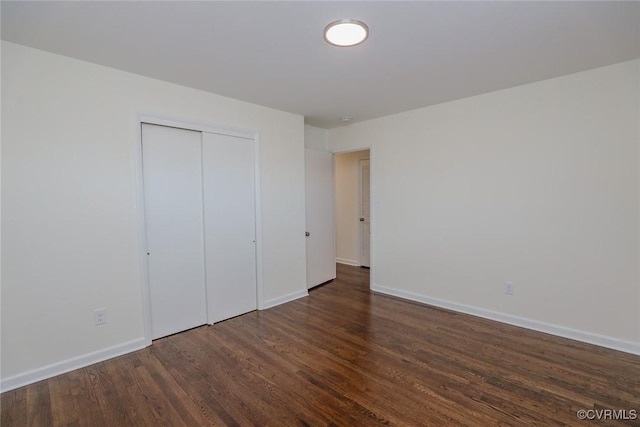 unfurnished bedroom featuring wood finished floors, baseboards, and a closet