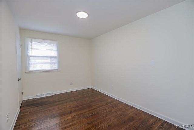 spare room featuring dark wood finished floors, baseboards, and visible vents