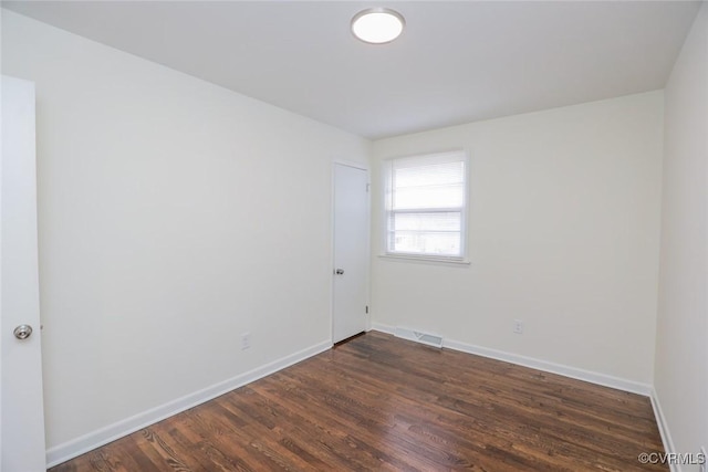 spare room with visible vents, dark wood-style floors, and baseboards