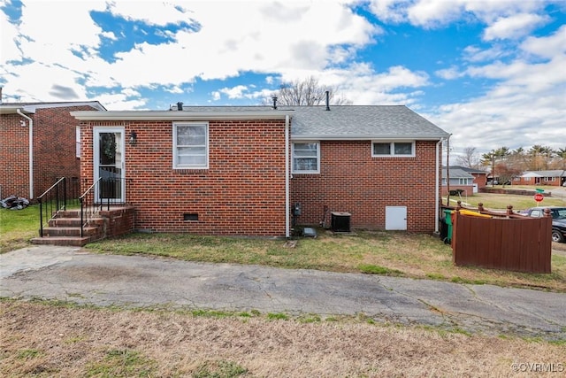 rear view of property featuring crawl space, brick siding, and a lawn