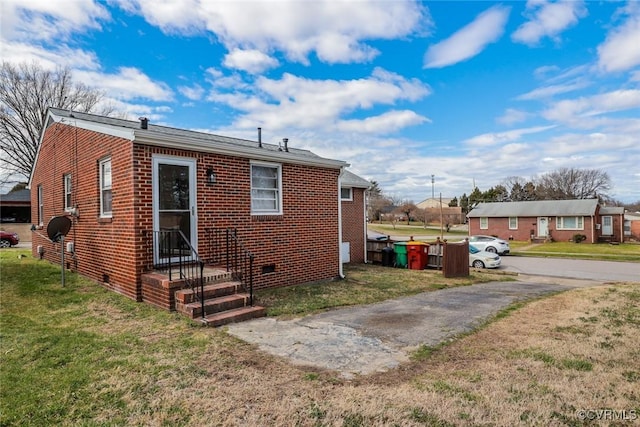 back of house featuring a yard, brick siding, and crawl space