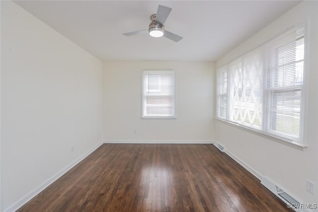 empty room featuring dark wood-type flooring, visible vents, baseboards, and ceiling fan