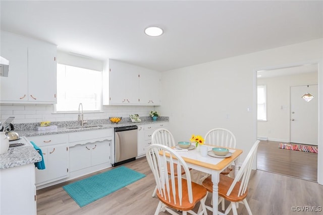 kitchen featuring dishwasher, light wood-type flooring, backsplash, and a sink