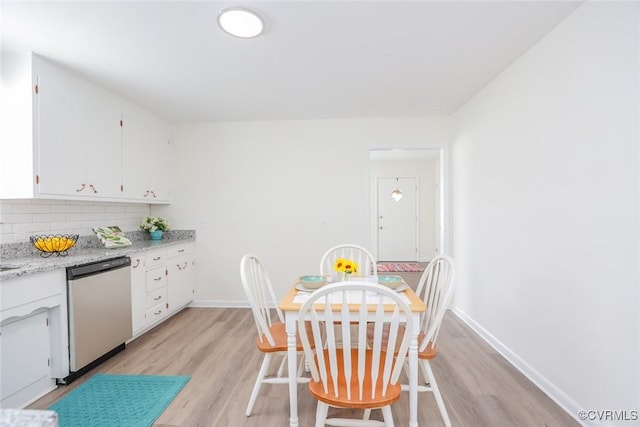 kitchen with baseboards, light wood finished floors, white cabinets, dishwasher, and backsplash