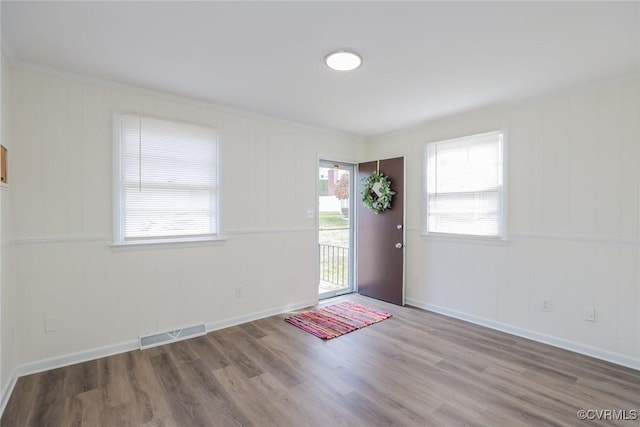 foyer featuring visible vents, baseboards, and wood finished floors