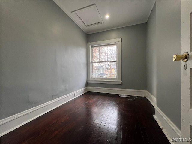 spare room with hardwood / wood-style flooring, attic access, and baseboards