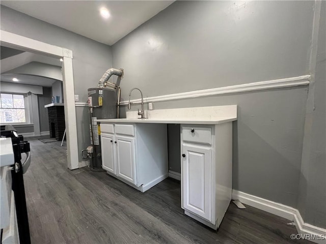 interior space featuring gas water heater, light countertops, dark wood-style flooring, and white cabinetry